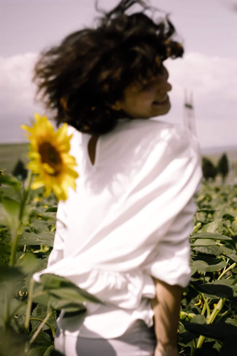 unfocused woman smiling over her shoulder in a sunflower field