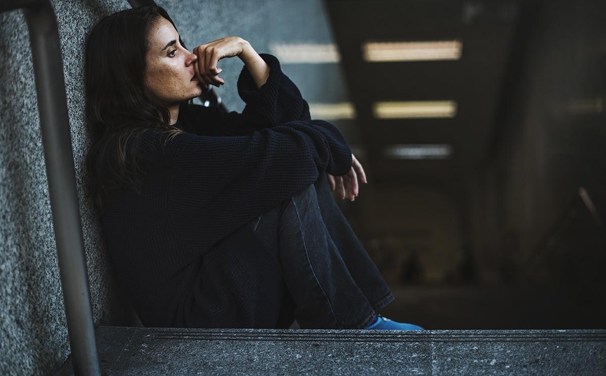 woman sits on steps and bites her nail while wondering do i have depression